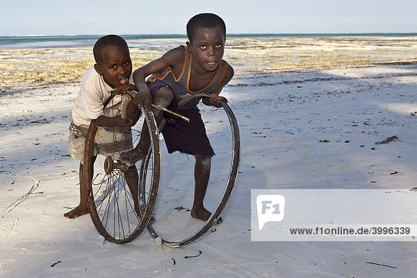 Kinder spielen mit alten Fahrradfelgen am Strand von Pingwe  Sansibar  Tansania  Afrika