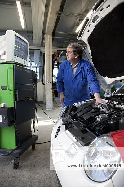 Master Craftsman of motor vehicle mechanics performing a diagnostics test on a car in a workshop