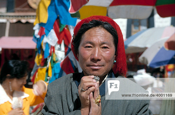 Tibetan man from the Kampha tribe with red hair knot  holding the symbol of the Tibetan snow lion as a trouser button with both hands  symbol contained in the Tibetan national flag  today banned in Tibet  Lhasa  Tibet  China  Asia