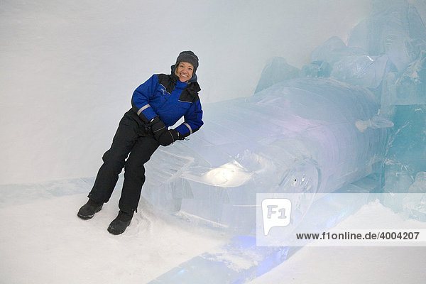 Eine Frau lehnt sich an ein Auto aus Eis im Eishotel in Jukkasjärvi  Lappland  Nord-Schweden  Schweden