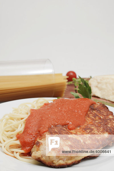 Milanese turkey steak on spaghetti with tomato sugo  piece of Parmesan cheese  spaghetti in glass