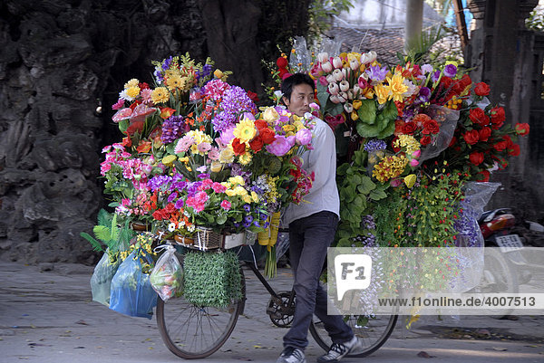 Blumenverkäufer schiebt Fahrrad überladen mit bunten Blumen  Hanoi  Vietnam  Asien