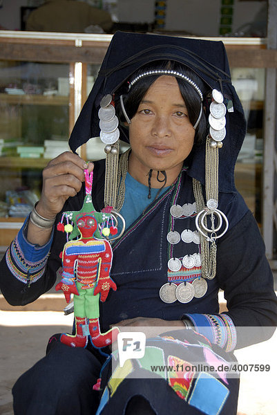Entwicklungshilfe Näherin der Akha Biladjo Frauen-Gruppe  Frau der Akha Pixor Ethnie in typischer Tracht präsentiert eine naive Puppe  Boun Neua  Phongsali Provinz  Laos  Südostasien  Asien