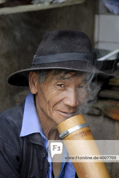 Portrait  ethnology  man of the Hani ethnic group wearing hat  smoker  smoking hookah  bong  near Xinji  Yuanyang  Yunnan Province  People's Republic of China  Asia