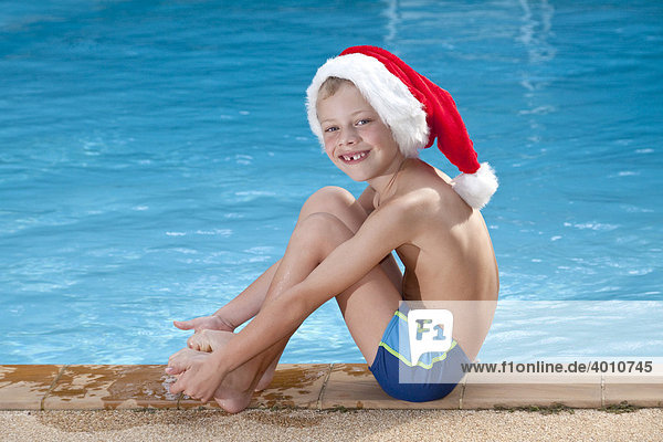Ein Junge mit Weihnachtsmütze an einem Pool Symbolbild