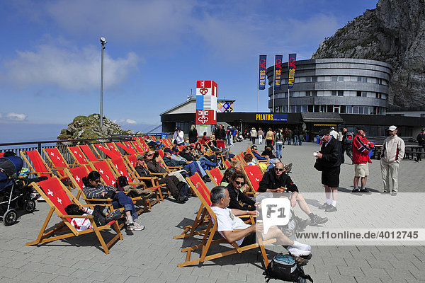 Touristen ruhen sich auf den Liegestühlen auf dem Gipfel des Pilatus  Ausflugsberg bei Luzern  aus  hinten das Hotel Bellevue  Schweiz  Europa