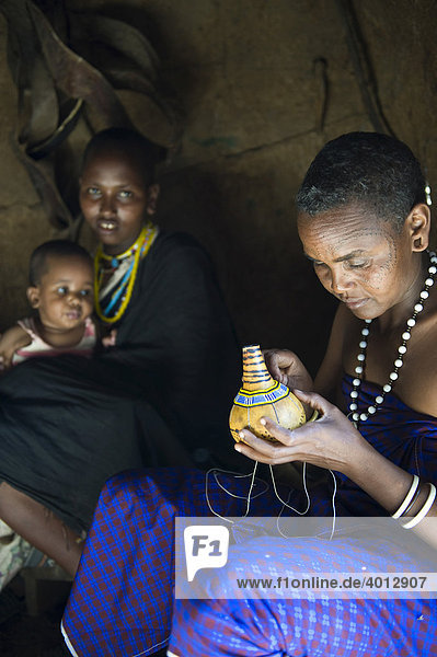 Eine Frau vom Stamm der Datooga dekoriert eine Kalebasse mit Glasperlen  Lake Eyassi  Tansania  Afrika
