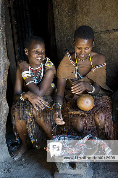Women of the Datooga tribe decorating a calabash with glass beads  Lake Eyassi  Tanzania  Africa