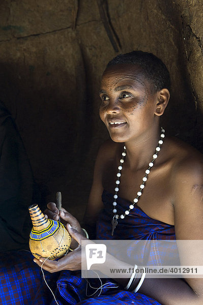 A woman of the Datooga tribe decorating a calabash with glass beads  Lake Eyassi  Tanzania  Africa