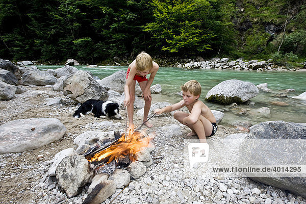 Children and a dog at a campfire on the banks of Brandenberger Ache River  North Tyrol  Austria  Europe
