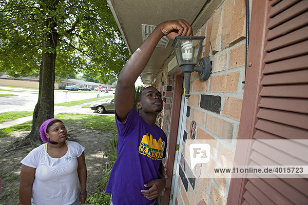 Volunteers from Xavier University replace incandescent light bulbs in a home with energy-saving compact fluorescent bulbs  Bridge City  Louisiana  USA