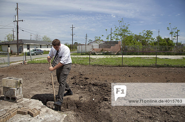 A Mormon missionary volunteers transforming a vacant lot in the lower ninth ward that was flooded by Hurricane Katrina into a community garden  New Orleans  Louisiana  USA