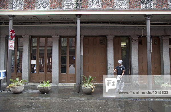 A man wearing a chef's hat cleans the sidewalk outside a restaurant in the French Quarter  New Orleans  Louisiana  USA