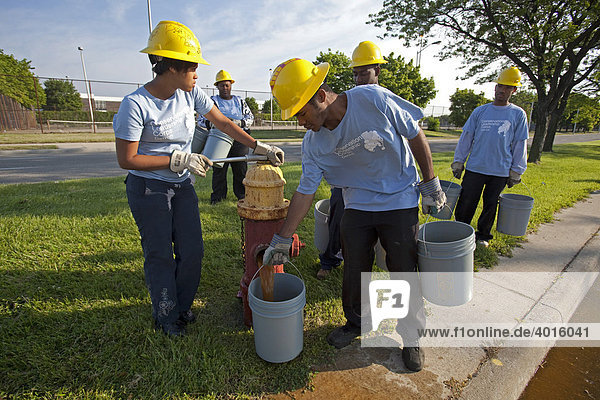 High school students fill buckets from a fire hydrant to water newly-planted trees as part of their summer jobs in the Conservation Leadership Corps  Detroit  Michigan  USA