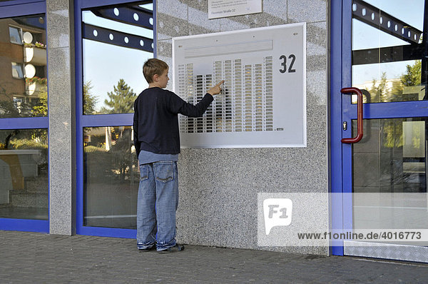 Ein neunjähriger Junge vor dem Klingelbrett eines Hochhauses  Trabantenstadt Chorweiler in Köln  Nordrhein-Westfalen  Deutschland  Europa