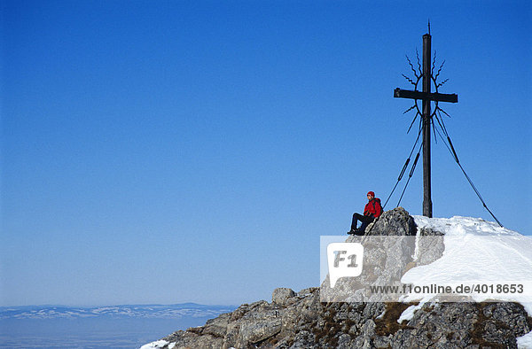 Eine Frau  22  am Gipfelkreuz des Steinernen Jägers in den Voralpen bei Reichraming im Winter  Oberösterreich  Österreich  Europa