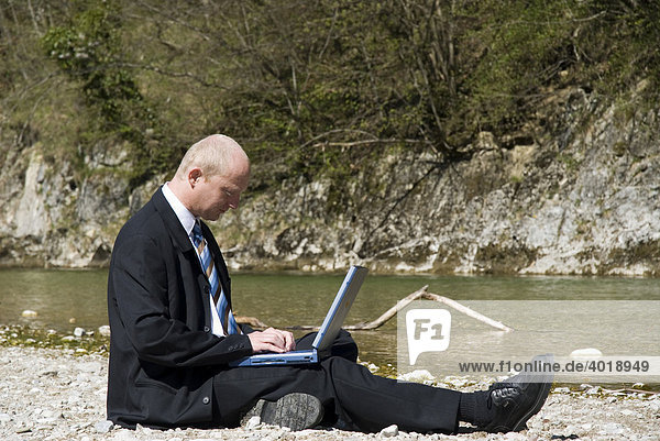 Businessman working next to a mountain brook