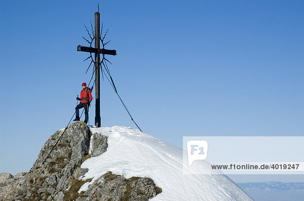 Eine Frau  22  am Gipfelkreuz des Steinernen Jäger in den Voralpen bei Reichraming im Winter  Oberösterreich  Österreich  Europa