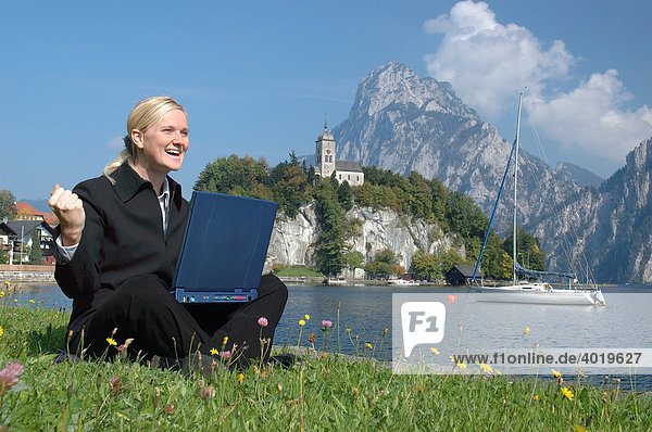 Blonde Frau im Anzug arbeitet im Freien am Laptop  am Ufer des Traunsees  Traunkirchen  Oberösterreich  Österreich  Europa