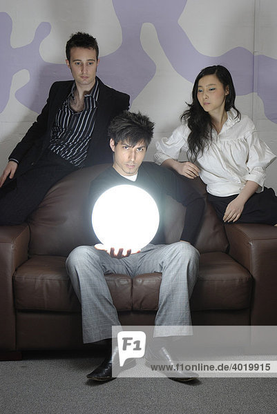 A young business man holding a brightly glowing globe with his colleagues looking