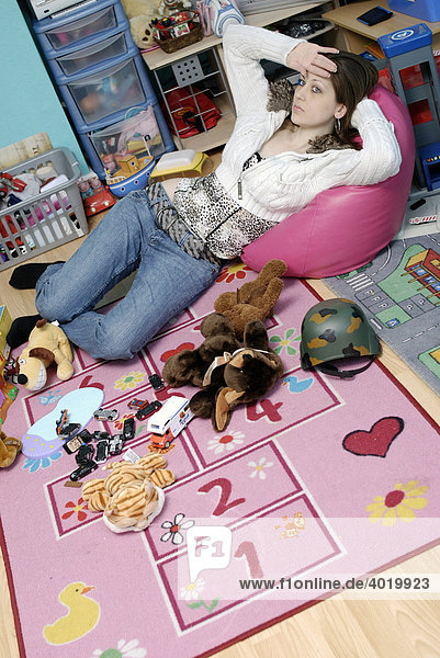 A weary young mum resting for a moment before tidying her children's messy playroom