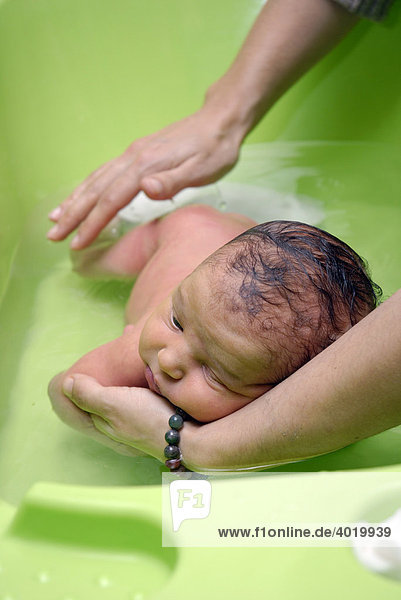 Ein Neugeborenes wird mit dem Gesicht nach unten gebadet