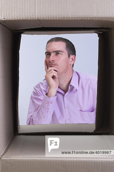 Thoughtful man seen through a box  symbolic for thinking outside the box  creative thought and lateral thinking