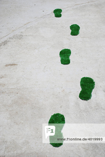 Green footprints over a concrete floor