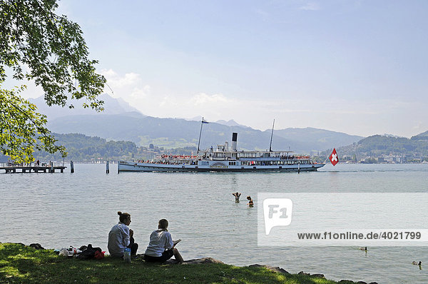 People  riverside  excursion boat  Vierwaldstaetter See or Lake Lucerne  Swiss flag  Lucerne  Switzerland  Europe