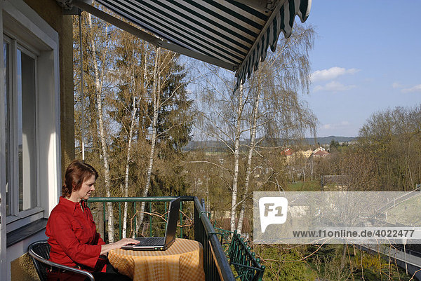 Woman working on a laptop  sitting on the balcony