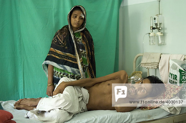 Als bei diesem Patienten vor einem halben Jahr Tuberkulose diagnostiziert wurde  sah er keinen Handlungsbedarf  weil er sich körperlich noch relativ gut fühlte. Aus Angst seine Familie während einer evtl. langwierigen und umständlichen Therapie im Stich zu lassen  wartete er bis es lebensgefährlich wurde. Jetzt liegt er auf Kosten einer Hilfsorganisation im privaten Shree Jain Hospital. Hinten steht seine Frau. Howrah  Hooghly  Westbengalen  Indien