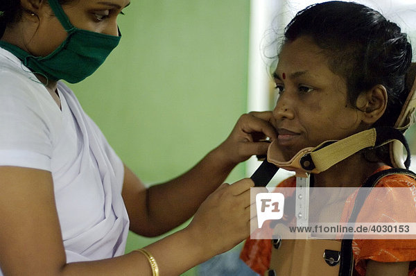 Im St. Thomas Home  einer Spezialklinik für Tuberkulose  lässt sich eine Frau geduldig von einer Schwester ein Stützkorsett anlegen. Sie leidet unter Spinaltuberkulose und ist vor kurzem auf Kosten einer Hilfsorganisation an der Wirbelsäule operiert worden. Howrah  Hooghly  Westbengalen  Indien