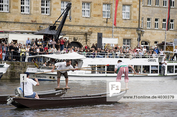 Men on boat taking part in the traditional fisherman jousting on the Regnitz River during the annual Sandkerwa fair  Bamberg  Upper Franconia  Bavaria  Germany  Europe