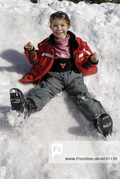 Laughing girl sliding down a snow covered hill  playing in snow