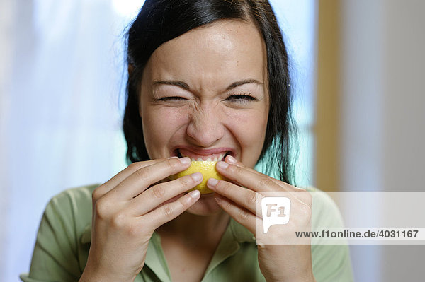 Junge Frau lutscht an einer Zitrone  Vitamin C  Sauer macht lustig