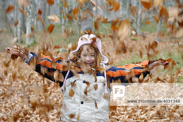 Kinder spielen im Herbst mit Laub