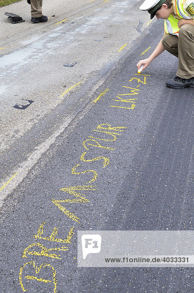 Young policewoman marking the road with crayon for accident expert after a road accident on a freeway  skidmark truck - witness  Altingen  Baden-Wuerttemberg  Germany  Europe