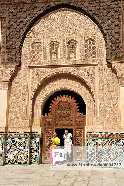 Tourists in front of a portal in the inner courtyard of the Ben Youssef Madrasah  Qur'an school  in the medina quarter of Marrakesh  Morocco  Africa