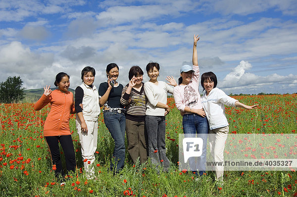 Group of young people in a field of red poppies  Kyrgystan  Central Asia