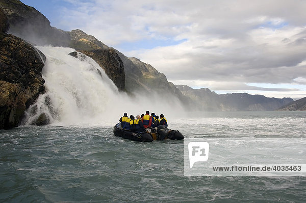Zodiac with tourists approaching a waterfall  Arsuk Fjord  Greenland  Denmark