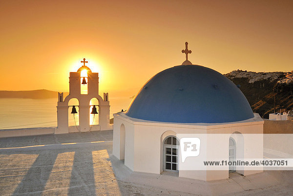 White Greek church with a blue dome and a bell tower at sunset Firostefani Santorini Cyclades Greece Europe