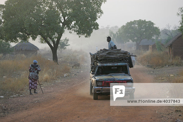 Schwer beladenes Auto auf der Dorfstraße  im morgendlichen Dunst  Houssere Faourou  Kamerun  Afrika