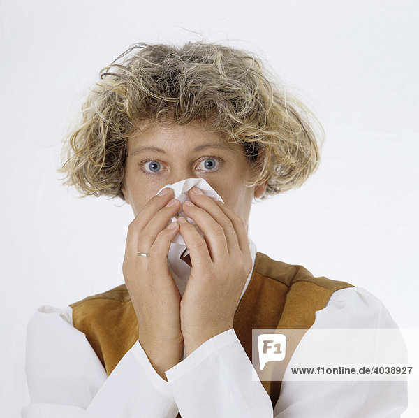 Blonde Frau putzt sich die Nase mit Papiertaschentuch