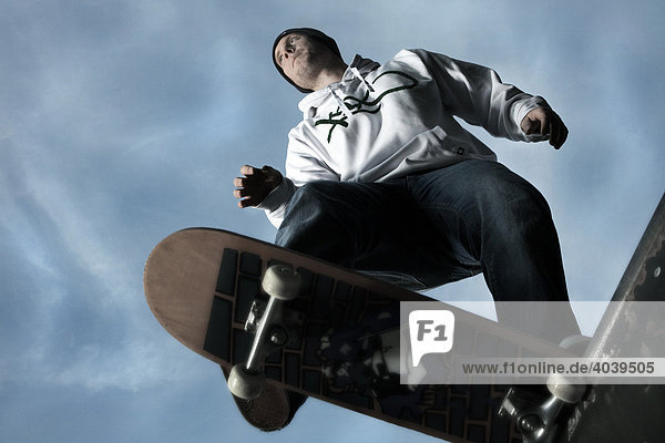 Junger Mann mit Skateboard kurz vor dem Sprung in die Hafepipe