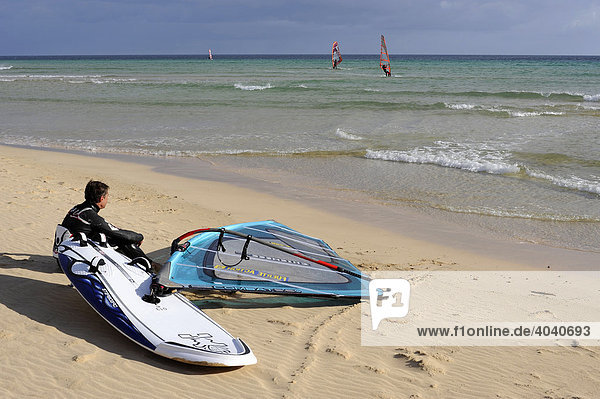 Windsurfer sitzt am Strand Playa de Sotavento de Jandia und beobachtet Sportler  Fuerteventura  Kanarische Inseln  Kanaren  Spanien  Europa