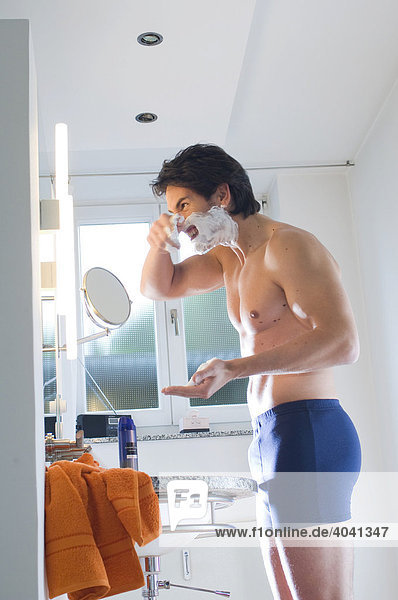 Mann in Unterhosen rasiert sich im Bad