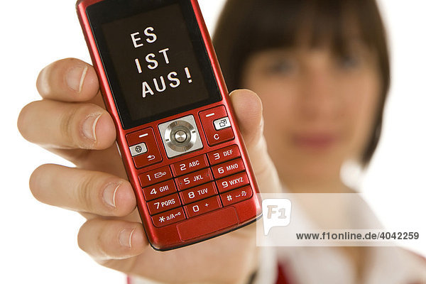 Twenty-year-old woman holding a mobile phone into the camera  with a message on the display  Es ist aus  It´s over