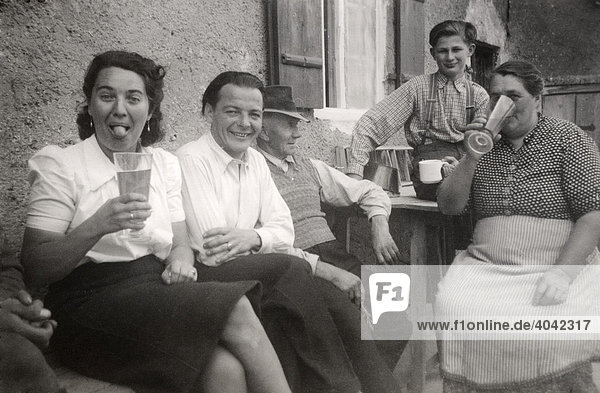 Historisches Foto: Personen sitzen vor dem Haus  trinken  1944