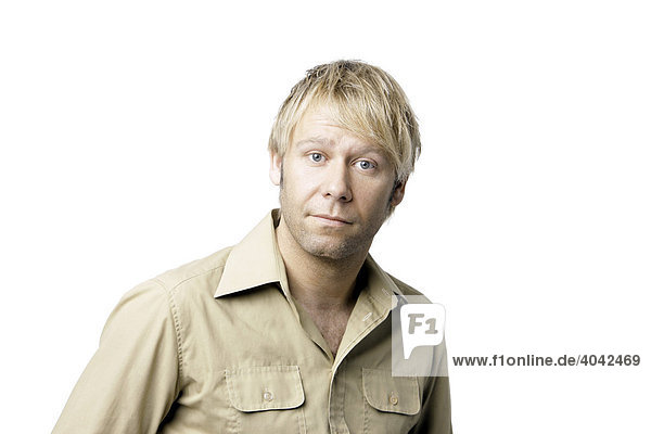Blonde man wearing a beige shirt looking into the camera