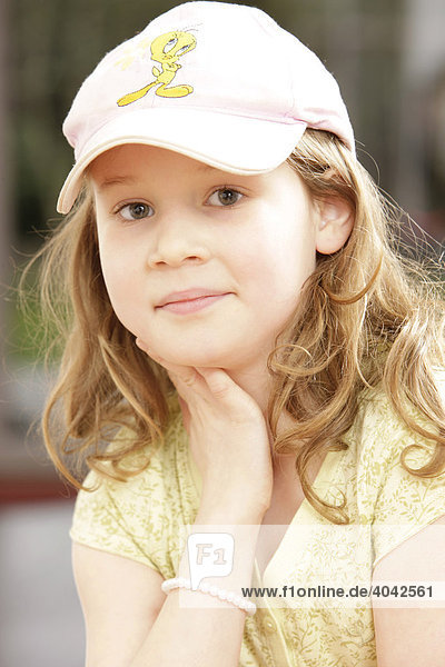 8-jähriges Mädchen mit Mütze  mit Hand am Gesicht